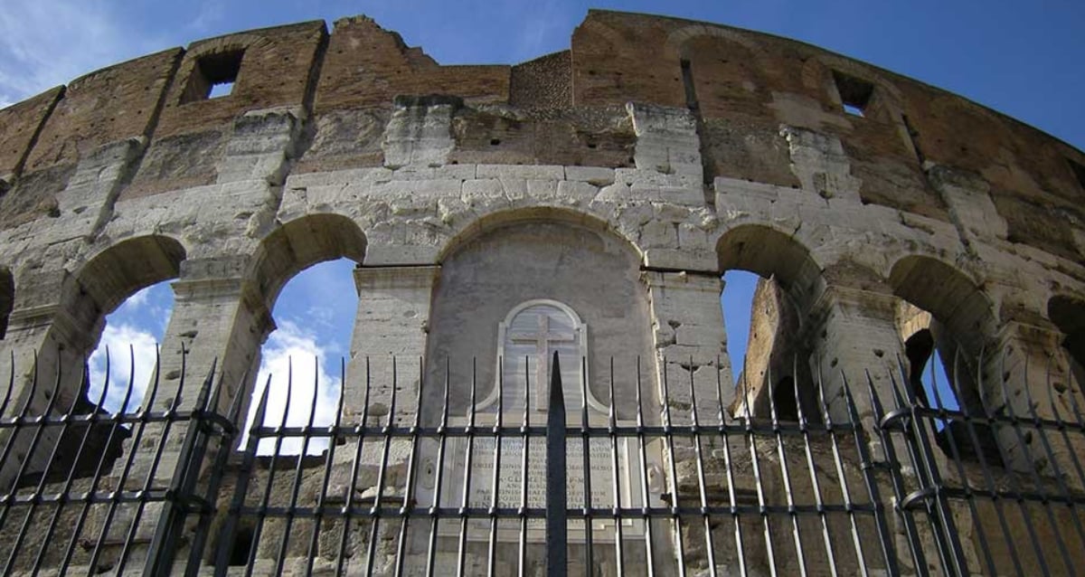 O turista americano se impala à cerca romana do Coliseu